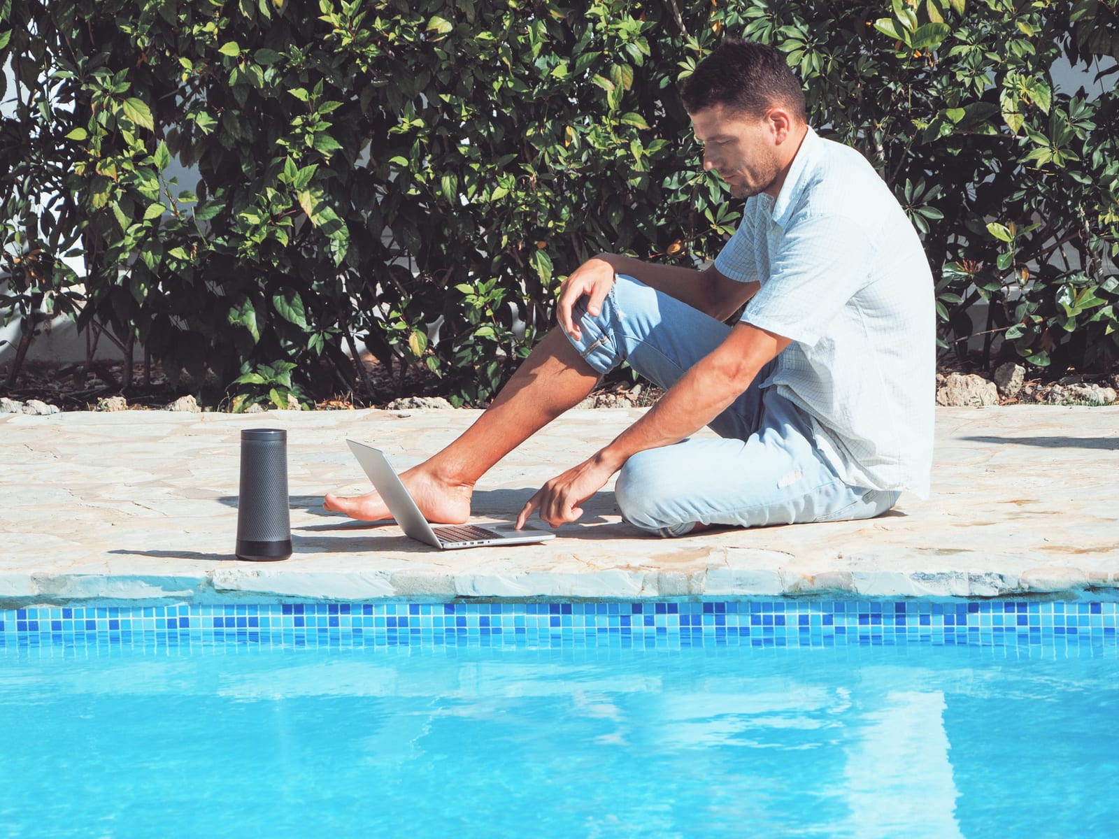 Pool service owner working on a laptop at the edge of a backyard pool — planning route profitability